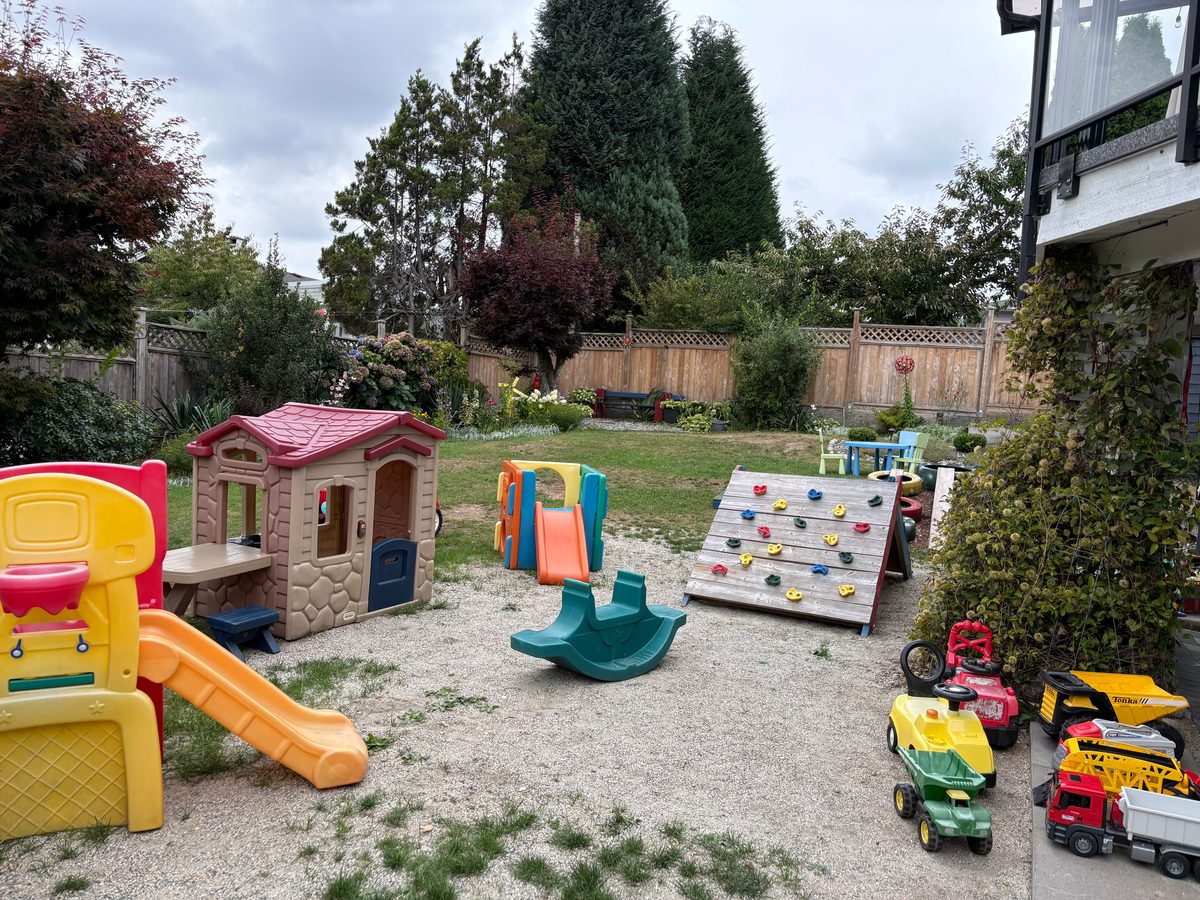 Fenced backyard with playhouse, slide, and climbing wall