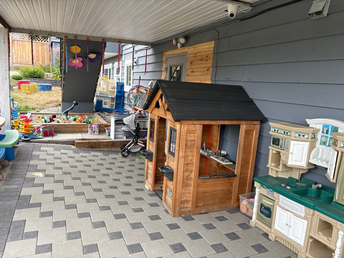Covered outdoor play area with wooden playhouse